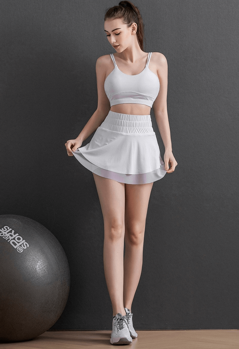 Woman in white high waist tennis skirt with hidden pockets, showcasing flexible fit, perfect for sports like yoga, running, or dancing.